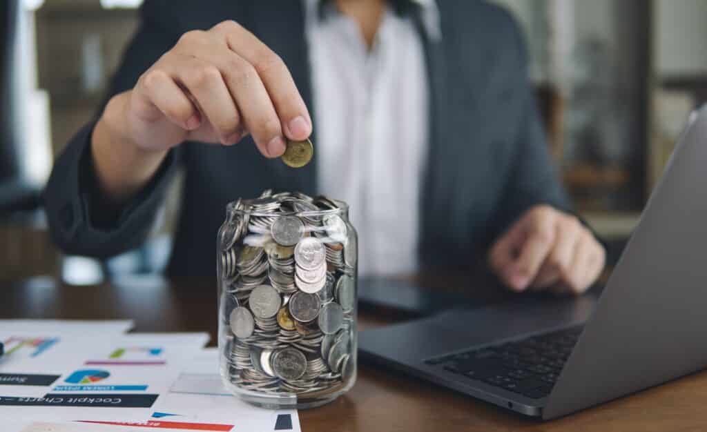 Business man putting coins in a jar for saving money on marketing conversions concept