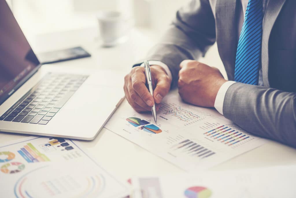 digital agency concept with man in a business suit looking through marketing data next to laptop.