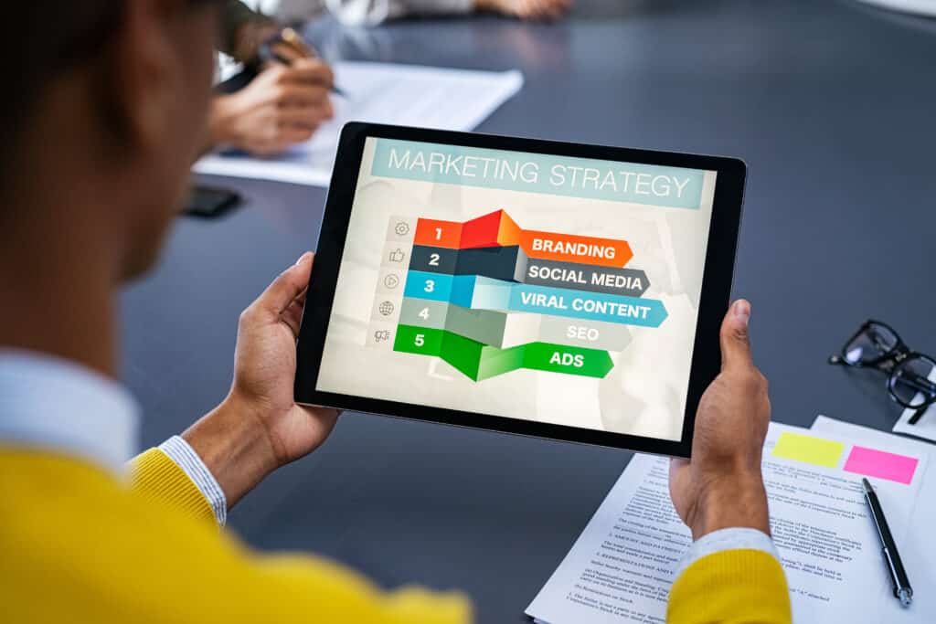 Man holding a tablet with marketing strategy items on the screen.